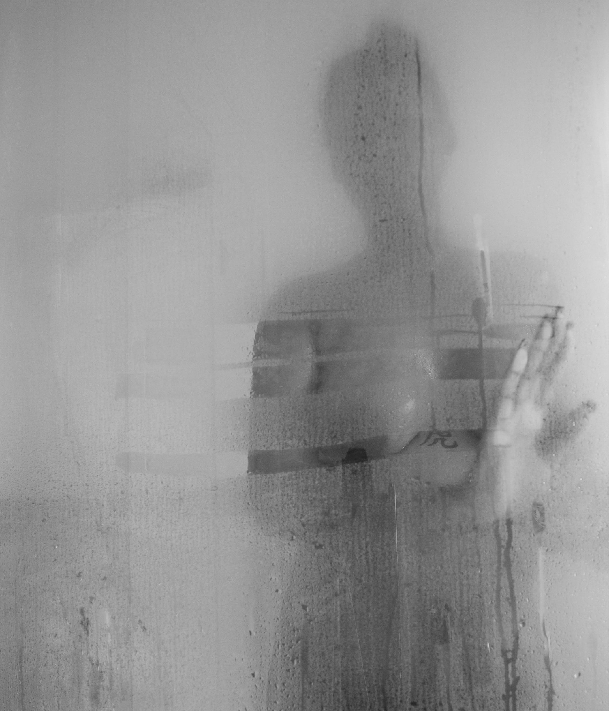 Naked woman in shower slightly visible through steam