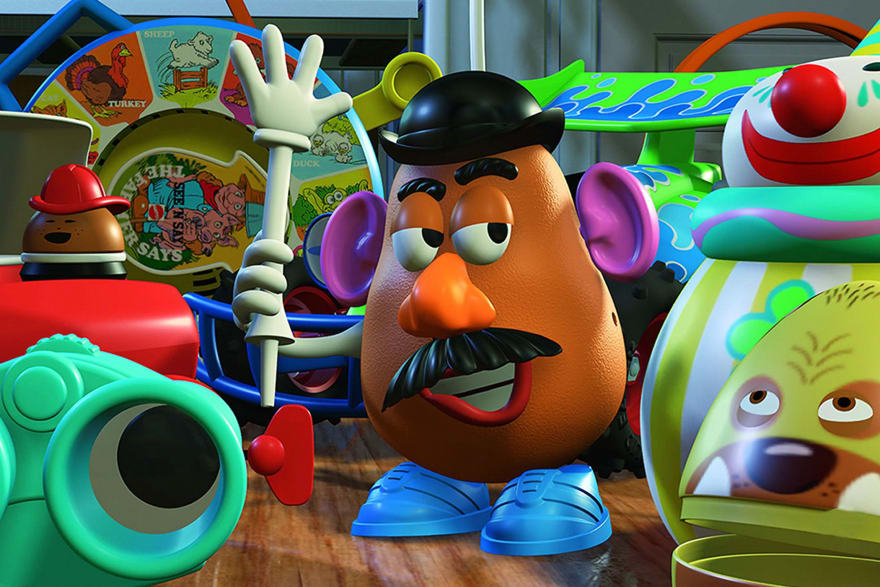 Mr Potato Head from Toy Story central with toys around him. He is holding a toy's arm.