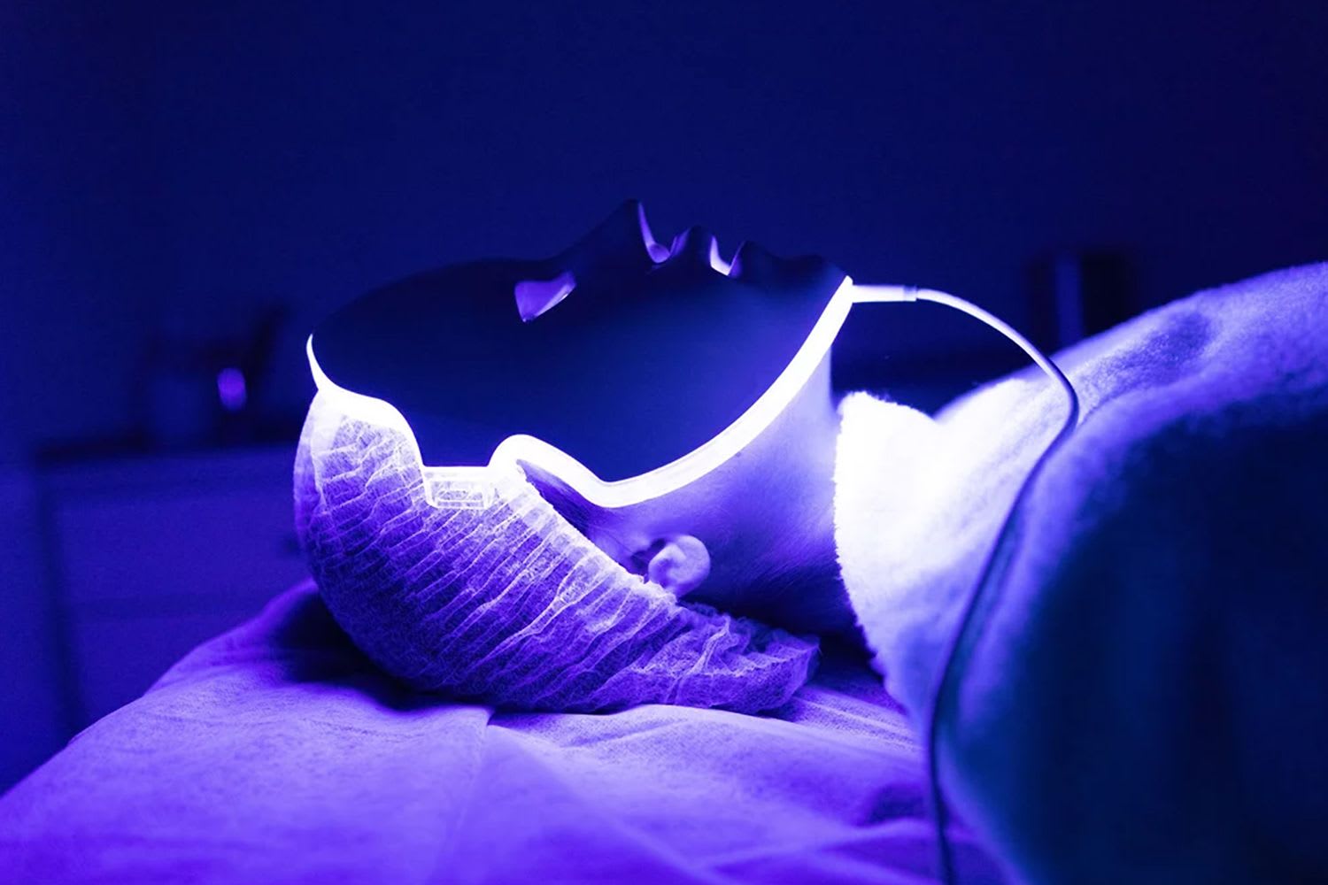 Woman laying back with an LED light therapy face mask